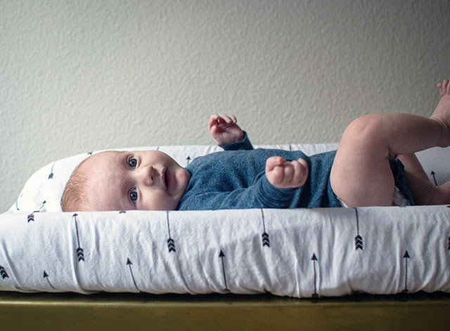 Un bébé confortablement installé sur sa table à langer